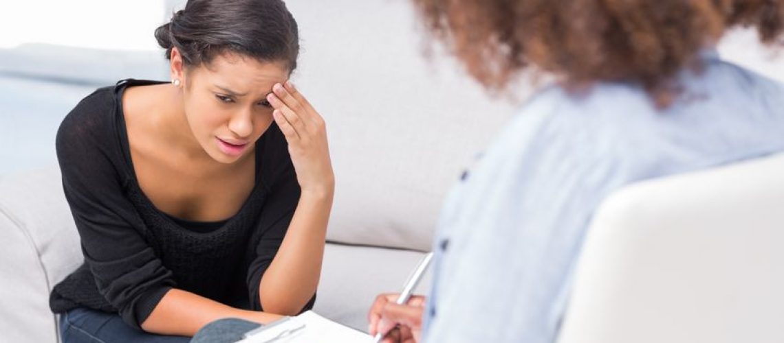 20468013 - woman crying on sofa during therapy session while therapist is taking notes